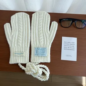 Close-up of cream knit mittens featuring cable patterns and a matching neck strap