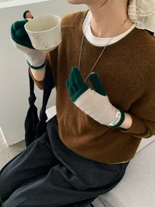 Detailed knit texture of dark green and beige fingerless gloves with brand tag