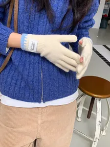 Close-up of beige knit gloves with blue striped cuffs and functional fingerless design