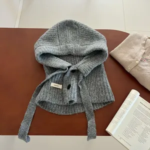 Détail de la cagoule en laine grise avec fermeture à bouton noir et étiquette tissée