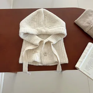 Texture de maille détaillée d'une cagoule en laine blanc crème avec boutons sur bois