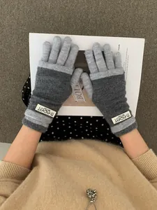 Close-up of contrast grey knit gloves with warm ribbed cuffs and brand logo detail