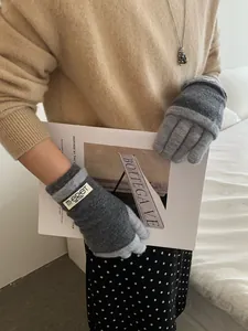 Detailed texture of grey knit gloves with MERET woven label and soft wool finish