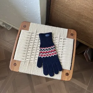 Nahaufnahme navy Fair-Isle Strickhandschuhe mit roten Mustern und Rippbündchen auf Holz