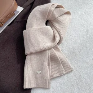 Detailed close-up of beige wool scarf featuring ribbed texture and metal brand tag