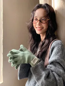 Close-up of soft sage green knit gloves with woven label and warm ribbed texture