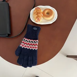 Detail von marineblauen Fair-Isle-Strickhandschuhen mit roten Jacquardmustern auf Holztisch