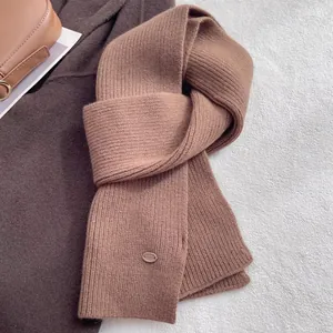 Close-up of dark brown ribbed knit wool scarf texture with small oval detail tag