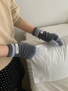 Close-up of contrast knit gloves in dark grey and light blue with woven brand label