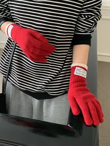 Detail of red ribbed knit gloves featuring a vintage rectangular wrist patch label