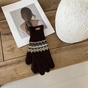 Nahaufnahme der dunkelbraunen Strickhandschuhe mit Fair-Isle-Muster und LUCKY-Etikett