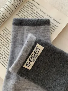 Close-up of thick knitted pumpkin orange gloves with warm wool texture and brand label