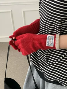 Detail of red knit gloves with white logo patch and contrast ribbed cuffs for winter