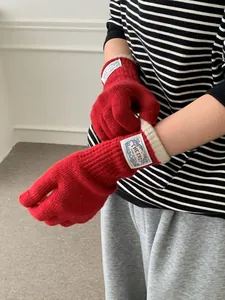 Detailed close-up of red knit gloves featuring an off-white ribbed cuff and woven brand label