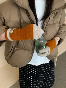 Close-up of caramel knit fingerless gloves with beige trim and white brand label
