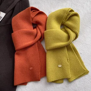 Detailansicht der orangefarbenen und senfgelben Wollschals mit hochwertigem Rippstrickmuster