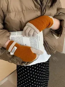 Close-up of orange and beige knitted gloves with brand label and soft wool texture