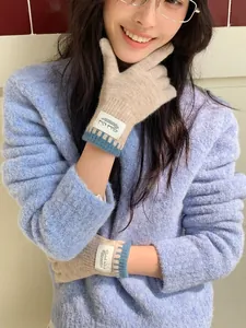 Detail of knitted winter gloves in khaki with blue striped cuffs and branded fabric label