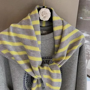 Detail of yellow and gray striped knitted shawl styled over a gray graphic sweatshirt