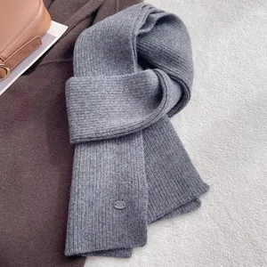 Detail of the grey knitted wool scarf showing rib-knit texture and elegant oval brand tag