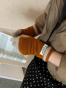 Detail of caramel and cream knitted arm warmers with m-eret label in a winter setting