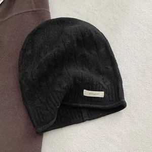 Detailaufnahme der schwarzen Strickmütze aus 100% Wolle mit Zopfmuster und Etikett