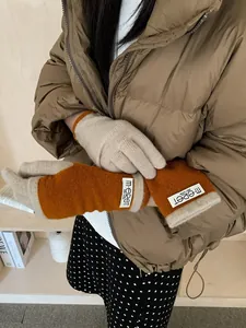 Close-up of beige and pumpkin orange knit gloves with a vintage woven brand label