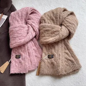 Detail of pink and camel cable knit wool scarves with thick textured braiding