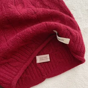 Detailansicht des 100% Wolle Etiketts und der Strickstruktur auf der roten Mütze