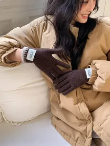 Detailed texture of dark brown knit gloves featuring a Silent Wind woven brand label