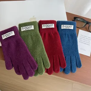 Detailed view of colorful knitted gloves in purple, green and burgundy with woven labels