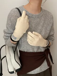 Detail of cream knit gloves with black contrast trim and vintage woven label on the wrist