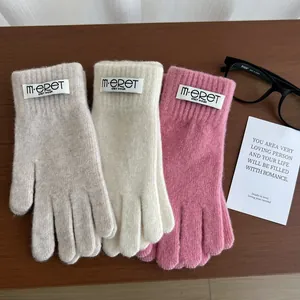 Detail of soft plush knit gloves with woven m-eret wear label in three pastel colors