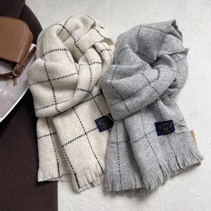 Detail of soft plaid cashmere-feel scarves with tassels in beige and grey tones