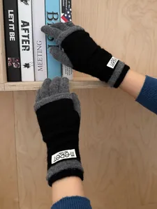 Detail of color-block knitted gloves in black and grey with woven brand label