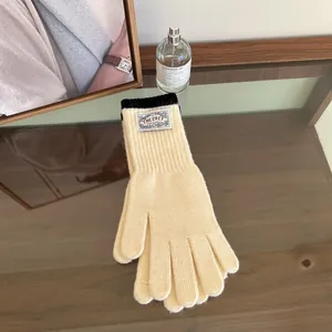 Detail of knit gloves featuring a vintage brand patch on ribbed cuffs and thick material