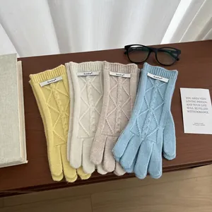 Detail of cable knit pattern and brand label on colorful merino wool gloves