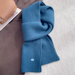 Macro shot of blue wool knitted scarf featuring vertical ribbed texture and small oval label