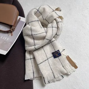Close-up of beige plaid scarf with tassels, leather brand tag and soft wool-like texture