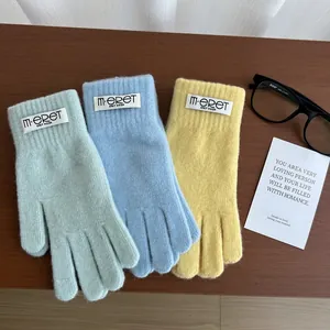 Detail of colorful knitted winter gloves in mint, blue, and yellow on a wooden desk
