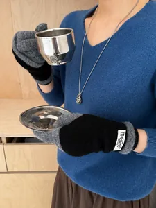 Detail of grey and black knit gloves with a flip-top design and white woven label