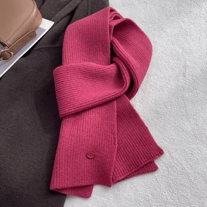 Detail eines magenta Schals aus reiner Wolle mit vertikaler Streifenstruktur und Logo