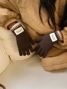 Detail of coffee brown knit gloves with beige contrast trim and woven Silent Wind label