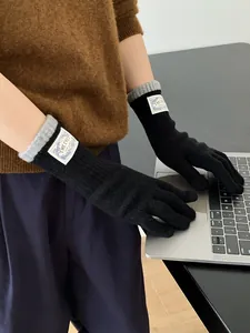 Detail of knit gloves with contrast gray cuffs and label while using a laptop