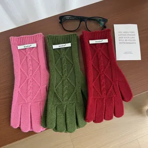 Close-up of cable knit merino wool gloves in red, green and pink with touch screen design