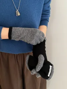 Close-up of color-block knitted touchscreen gloves in gray and black with woven labels
