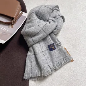 Close-up of grey plaid cashmere scarf featuring thick fringes and a quality fabric label