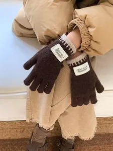 Detail of warm brown knit gloves featuring a Silent Wind fabric label and striped wrist cuffs