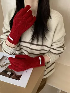 Detail of red merino wool knitted gloves with textured diamond pattern and wrist label