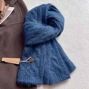 Close-up of deep blue wool blend knit scarf with brand label and Kraft paper gift tag